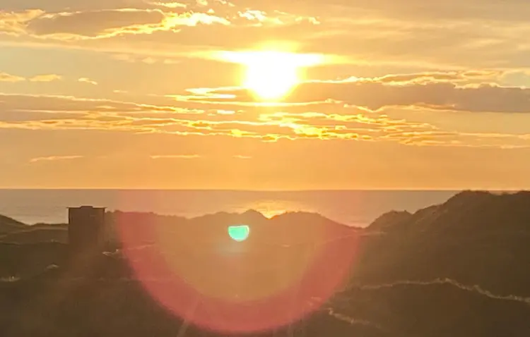 Sonnenuntergang mit goldenem Himmel über Meer und Dünen